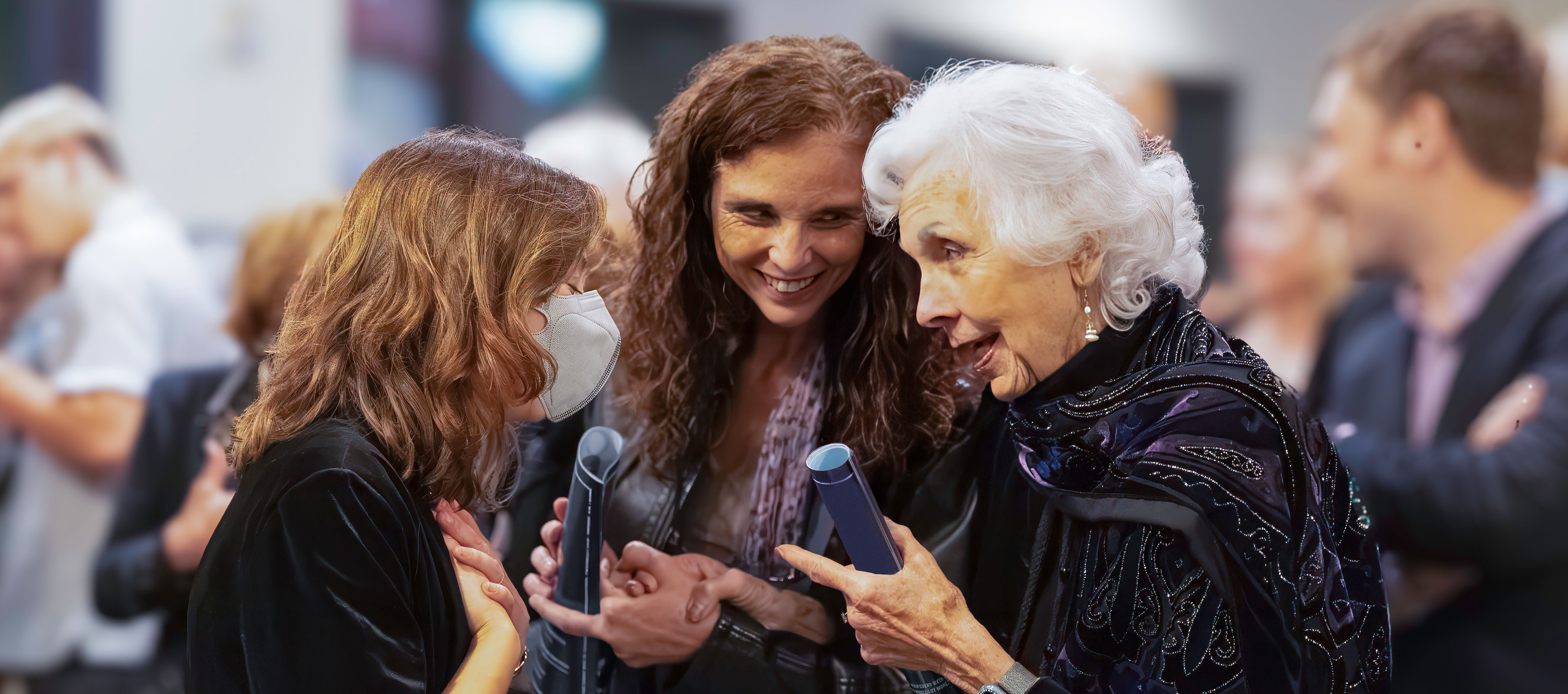 Three women smiling and having an intimate conversation in the lobby after a show. (Photo by Allison Paraiso/Berkeley Rep)