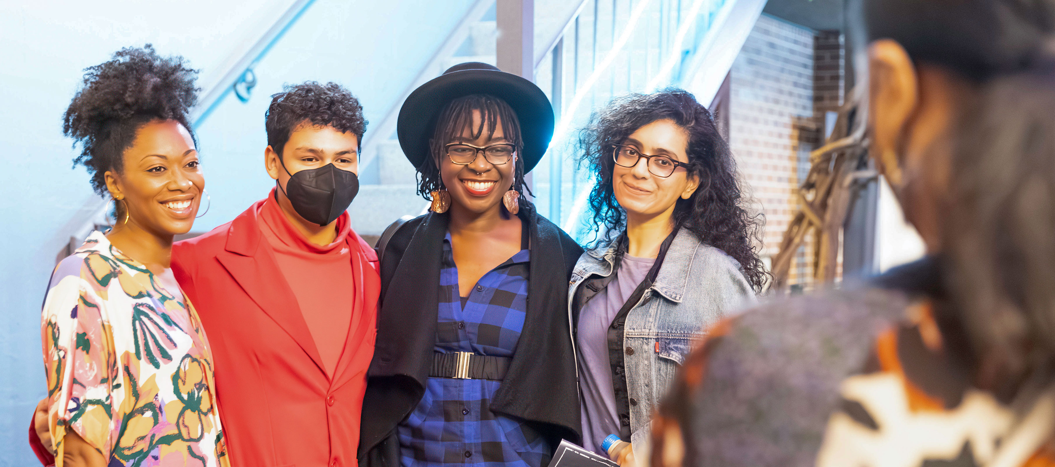 Four diverse young adults posing together for a picture in the Narsai M. David Courtyard. (Photo by Allison Paraiso/Berkeley Rep)